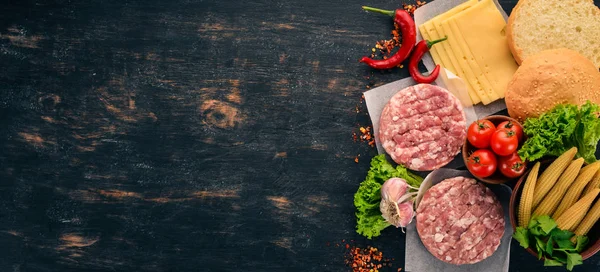 Raw burger Cooking a burger with meat. On a black wooden background. Top view. Free copy space.