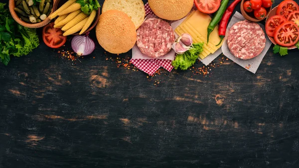 Raw burger Cooking a burger with meat. On a black wooden background. Top view. Free copy space.