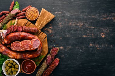 Sosis Fuet, salam, karton mutfak gemide. Siyah bir arka plan üzerinde. Üstten görünüm. Metniniz için boş alan.