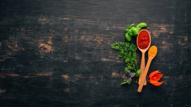 Baharatlar ve otlar kümesi. Hint Mutfak. Biber, tuz, kırmızı biber, fesleğen, zerdeçal. Siyah ahşap tahta. Üstten görünüm. Ücretsiz kopya alanı.