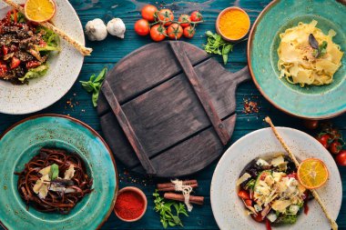 Yemekleri kümesi. Parmesan peyniri ve sebze salatası ve mavi peynirli makarna. Üstten görünüm. Metniniz için boş alan. Ahşap bir arka plan üzerinde.