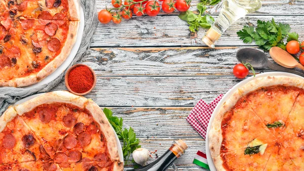 A set of Italian pizza. Italian cuisine. On a white wooden background. Free copy space. Top view.