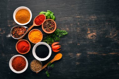 Baharatlar ve otlar kümesi. Hint Mutfak. Biber, tuz, kırmızı biber, fesleğen, zerdeçal. Siyah ahşap tahta. Üstten görünüm. Ücretsiz kopya alanı.