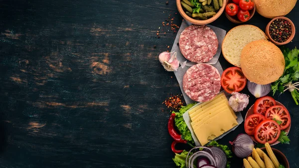 Raw burger Cooking a burger with meat. On a black wooden background. Top view. Free copy space.