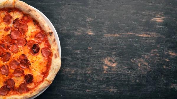 Pizza Margarita with sausages and tomato sauce. On a wooden background. Top view. Free space for your text.