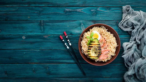 Asian food. Noodles with shrimps, avocados, eggs and chia seeds. On a wooden background. Top view. Free copy space.
