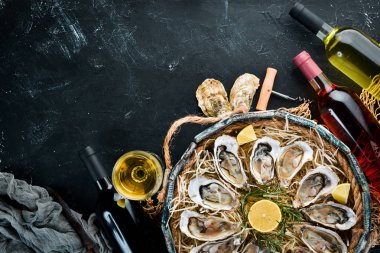 Ahşap kutuda limon ile taze istiridye. Siyah taş arka planda. Üst görünüm. Ücretsiz kopya alanı.