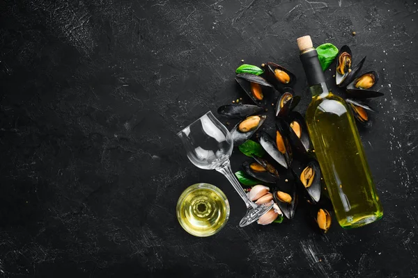 A bottle of white wine and mussels. Top view. Free space for your text. On the old background.