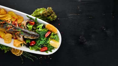 Alabalık pişmiş patates ve sebzeler ile. Ahşap bir arka plan üzerinde. Üstten Görünüm. Ücretsiz kopya alanı