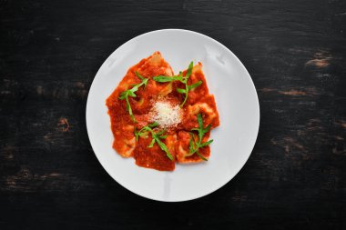 Domates sosu ve Parmesan peyniri ile klasik mantı. İtalyan mutfağı. Köfte. Tabağa ahşap arka plan. Üstten Görünüm. Ücretsiz kopya alanı.