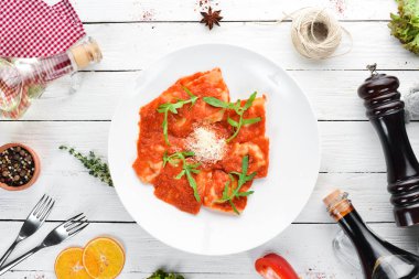 Domates sosu ve Parmesan peyniri ile klasik mantı. İtalyan mutfağı. Köfte. Tabağa ahşap arka plan. Üstten Görünüm. Ücretsiz kopya alanı.