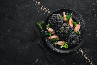 Siyah bir tabak karides ile siyah makarna. Üstten Görünüm. Beyaz ahşap zemin üzerinde. Ücretsiz kopya alanı.