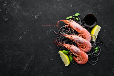 Siyah siyah bir taş zemin üzerine Karidesli Makarna. Üstten Görünüm. Metniniz için boş alan.