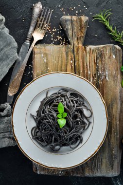 Siyah makarna bir tabak üzerine. Üstten Görünüm. Beyaz ahşap zemin üzerinde. Ücretsiz kopya alanı.