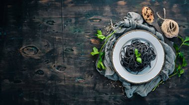 Siyah makarna bir tabak üzerine. Üstten Görünüm. Beyaz ahşap zemin üzerinde. Ücretsiz kopya alanı.