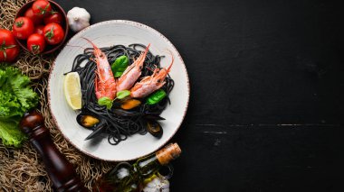Siyah spagetti. Deniz ürünleri ve limon ile siyah makarnalar. Karides ve midye. Eski arka plan üzerinde. Üstten Görünüm. Metniniz için boş alan.