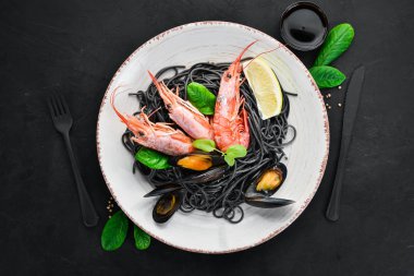 Siyah spagetti. Deniz ürünleri ve limon ile siyah makarnalar. Karides ve midye. Eski arka plan üzerinde. Üstten Görünüm. Metniniz için boş alan.