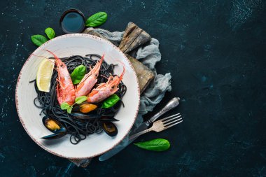 Siyah spagetti. Deniz ürünleri ve limon ile siyah makarnalar. Karides ve midye. Eski arka plan üzerinde. Üstten Görünüm. Metniniz için boş alan.