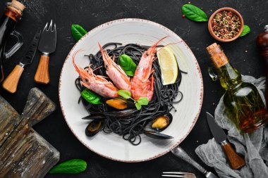 Siyah spagetti. Deniz ürünleri ve limon ile siyah makarnalar. Karides ve midye. Eski arka plan üzerinde. Üstten Görünüm. Metniniz için boş alan.