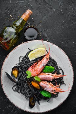 Siyah spagetti. Deniz ürünleri ve limon ile siyah makarnalar. Karides ve midye. Eski arka plan üzerinde. Üstten Görünüm. Metniniz için boş alan.