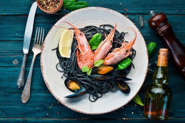 Siyah spagetti. Deniz ürünleri ve limon ile siyah makarnalar. Karides ve midye. Eski arka plan üzerinde. Üstten Görünüm. Metniniz için boş alan.