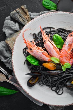 Siyah spagetti. Deniz ürünleri ve limon ile siyah makarnalar. Karides ve midye. Eski arka plan üzerinde. Üstten Görünüm. Metniniz için boş alan.