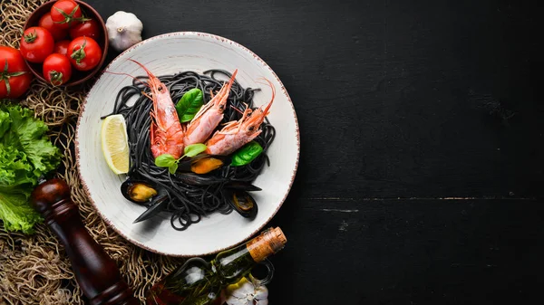 Siyah spagetti. Deniz ürünleri ve limon ile siyah makarnalar. Karides ve midye. Eski arka plan üzerinde. Üstten Görünüm. Metniniz için boş alan.