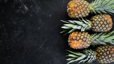 Siyah bir taş zemin üzerine taze ananas. Üstten Görünüm. Ücretsiz kopya alanı.