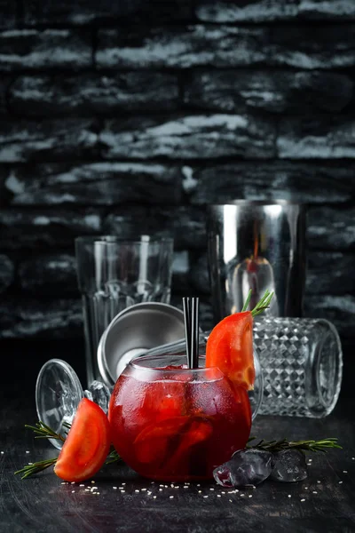 Tomato cocktail. Gin, cranberry juice, tomatoes, ice. On a wooden background. Top view.