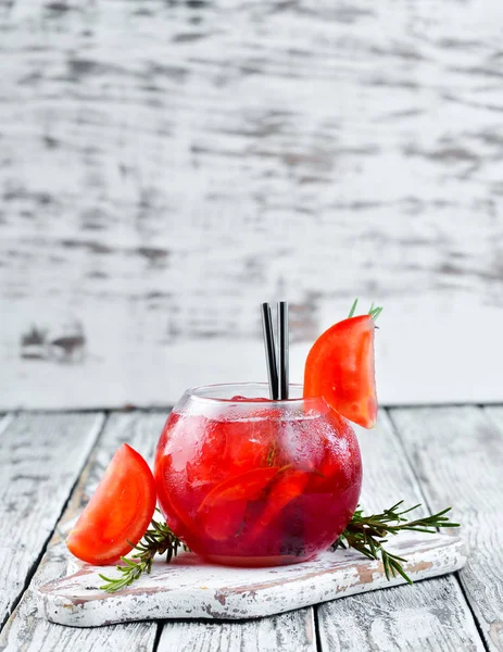 Tomato cocktail. Gin, cranberry juice, tomatoes, ice. On a wooden background. Top view.