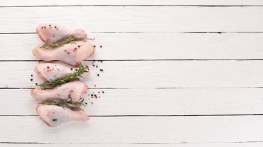 Çiğ tavuk budu ve baharat ve otlar. Barbekü. Beyaz ahşap zemin üzerinde. Üstten Görünüm. Ücretsiz kopya alanı.