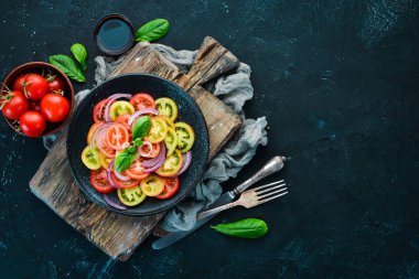 Taze domates ve soğan bir siyah plaka salata. Eski arka plan üzerinde. Üstten Görünüm. Metniniz için boş alan.