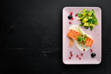 Bir tabakta sebze ile pişmiş somon fileto. Ahşap bir arka plan üzerinde. Üstten Görünüm. Metniniz için boş alan.