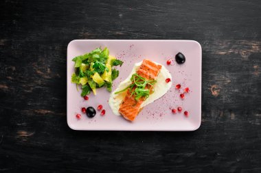 Bir tabakta sebze ile pişmiş somon fileto. Ahşap bir arka plan üzerinde. Üstten Görünüm. Metniniz için boş alan.