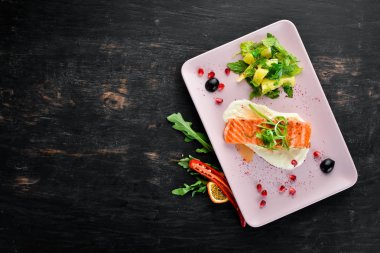 Bir tabakta sebze ile pişmiş somon fileto. Ahşap bir arka plan üzerinde. Üstten Görünüm. Metniniz için boş alan.