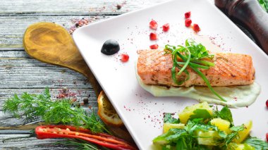 Bir tabakta sebze ile pişmiş somon fileto. Ahşap bir arka plan üzerinde. Üstten Görünüm. Metniniz için boş alan.