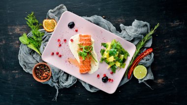 Bir tabakta sebze ile pişmiş somon fileto. Ahşap bir arka plan üzerinde. Üstten Görünüm. Metniniz için boş alan.