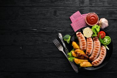 Patates ve sebze siyah taş zemin ile ızgara sosis. Et. Üstten Görünüm. Ücretsiz kopya alanı.