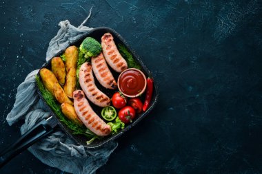Patates ve sebze siyah taş zemin ile ızgara sosis. Et. Üstten Görünüm. Ücretsiz kopya alanı.
