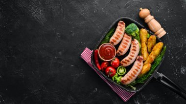 Patates ve sebze siyah taş zemin ile ızgara sosis. Et. Üstten Görünüm. Ücretsiz kopya alanı.