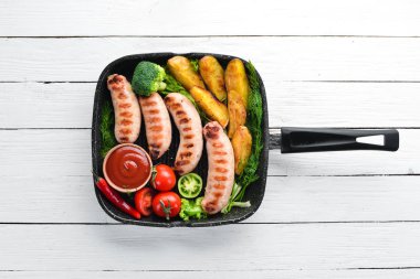 Patates ve sebze siyah taş zemin ile ızgara sosis. Et. Üstten Görünüm. Ücretsiz kopya alanı.