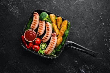 Patates ve sebze siyah taş zemin ile ızgara sosis. Et. Üstten Görünüm. Ücretsiz kopya alanı.