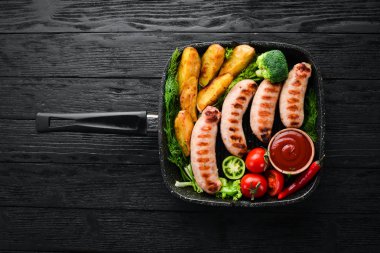 Patates ve sebze siyah taş zemin ile ızgara sosis. Et. Üstten Görünüm. Ücretsiz kopya alanı.