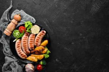 Patates ve sebze siyah taş zemin ile ızgara sosis. Et. Üstten Görünüm. Ücretsiz kopya alanı.