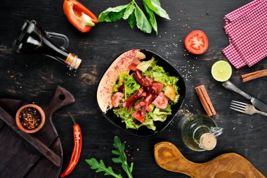 Salata taze sebze ve sosis siyah bir tabak içinde. Ahşap bir arka plan üzerinde. Üstten Görünüm. Metniniz için boş alan.