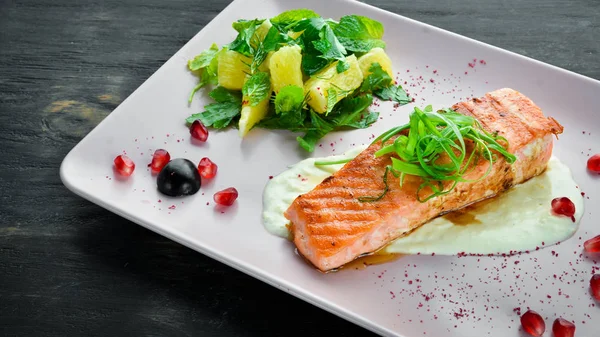 Bir tabakta sebze ile pişmiş somon fileto. Ahşap bir arka plan üzerinde. Üstten Görünüm. Metniniz için boş alan.