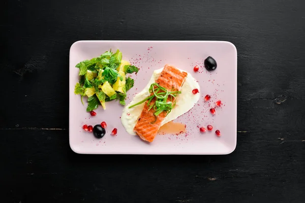 Bir tabakta sebze ile pişmiş somon fileto. Ahşap bir arka plan üzerinde. Üstten Görünüm. Metniniz için boş alan.