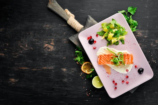 Bir tabakta sebze ile pişmiş somon fileto. Ahşap bir arka plan üzerinde. Üstten Görünüm. Metniniz için boş alan.