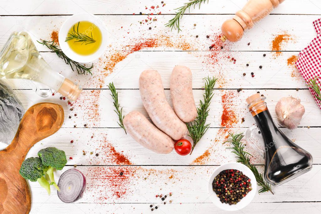 Raw sausages with spices and herbs. Barbecue. On a black stone background. Top view. Free copy space.