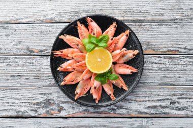 Beyaz bir arka planda ahşap plaka üzerinde limonlu çiğ karides. Üstten Görünüm. Ücretsiz kopya alanı